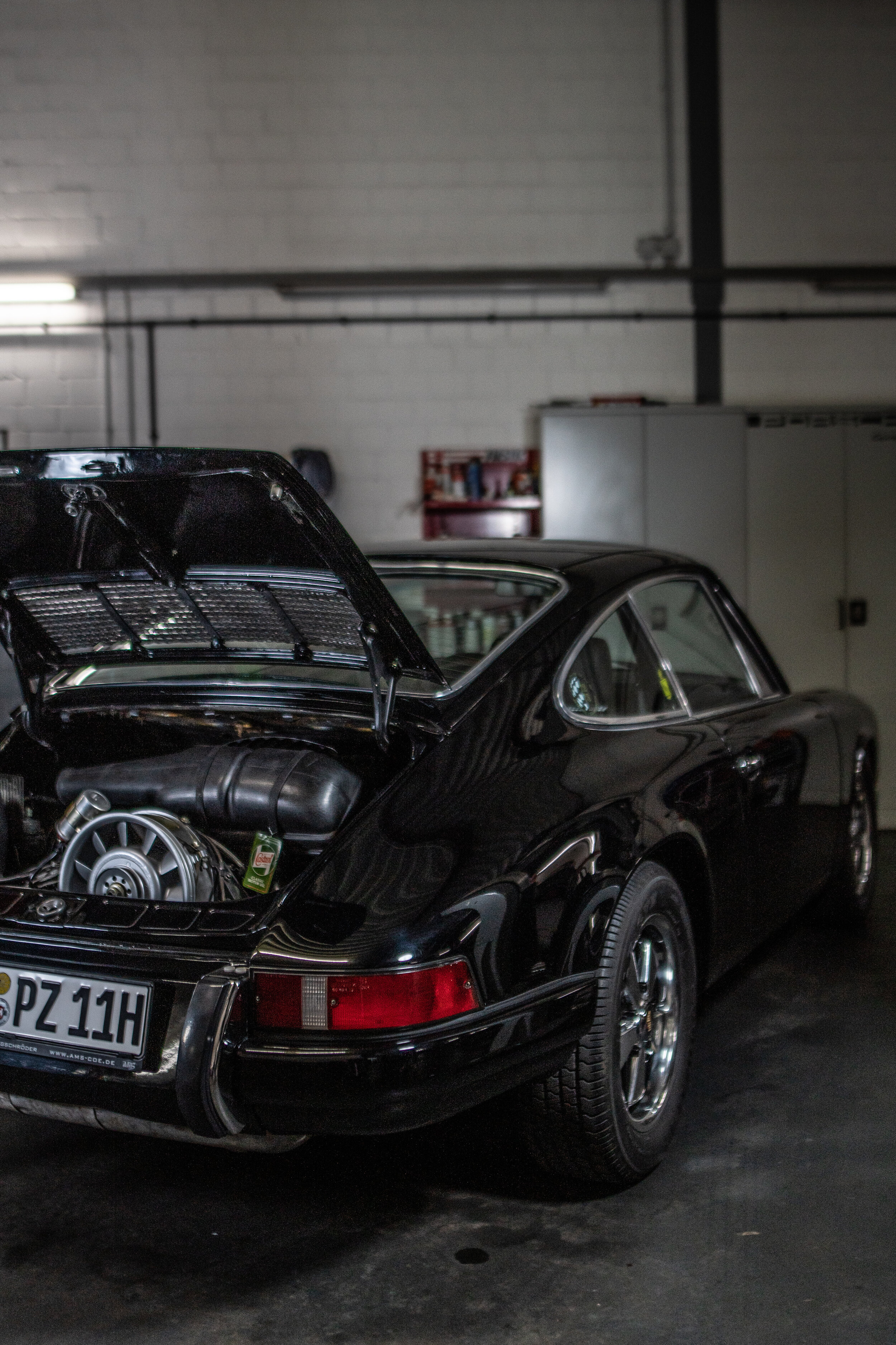 Schwarzer Porsche 911 der ersten Generation mit geöffneter Front- und Motorhaube in der AMS Werkstatt